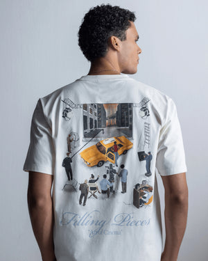 A man shown from the back wearing a white graphic t-shirt with a large collage print featuring a yellow taxi, film crew, and the text 'Filling Pieces' and ' Art of Cinema'.